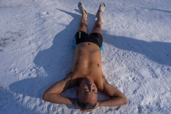 A winter swimmer lies on snow before taking to the water in Harbin in China's Heilongjiang province on Sunday, Jan. 4, 2026. (AP Photo/Ng Han Guan)