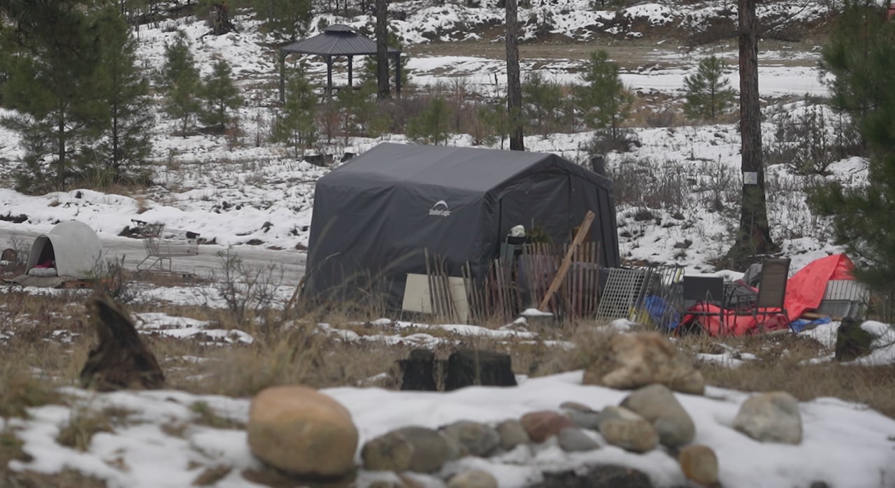 Tents and paraphernalia are seen in a snowy field.