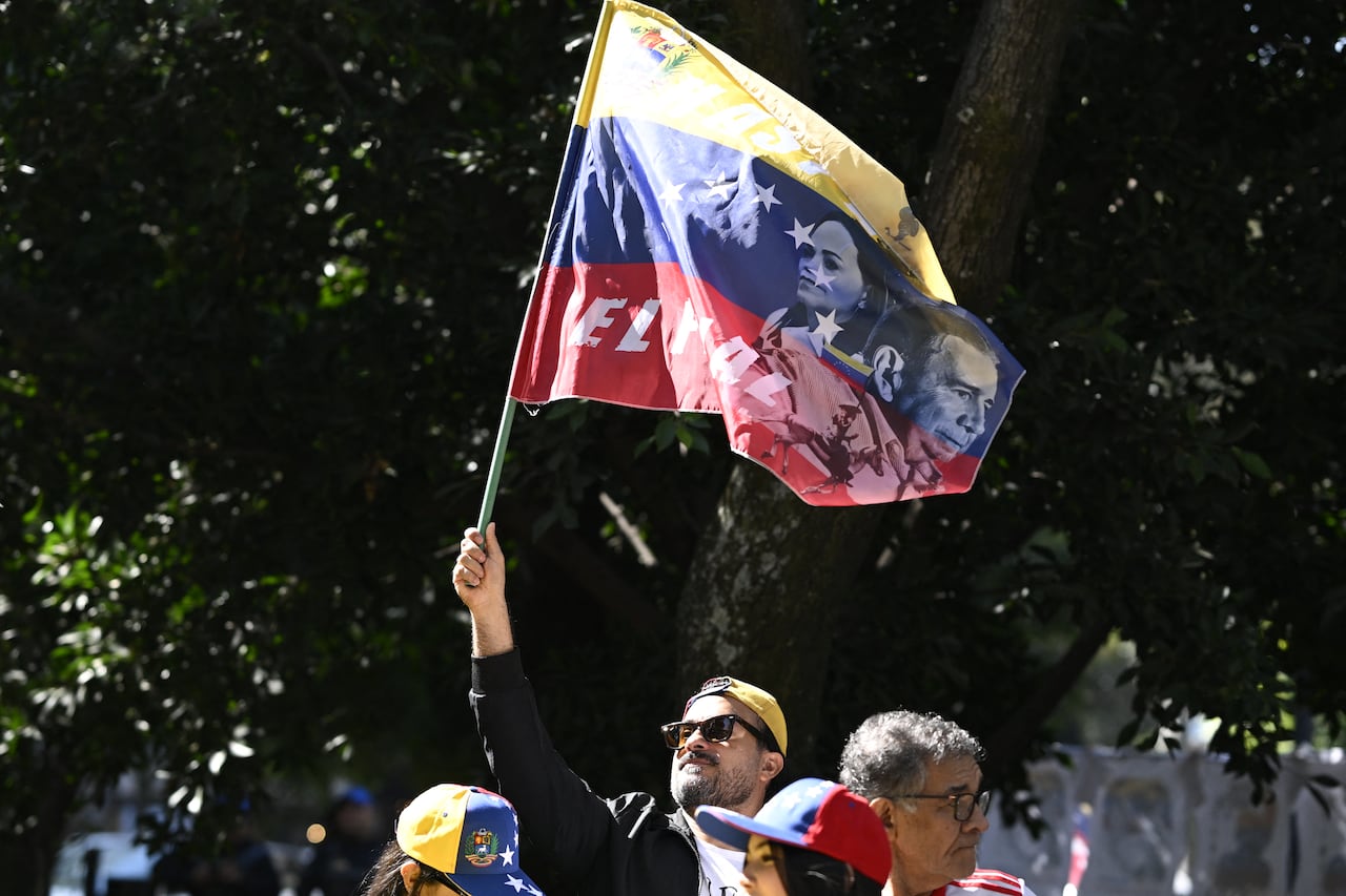 A man waves a red, yellow and blue flag with a man and woman's face on it 