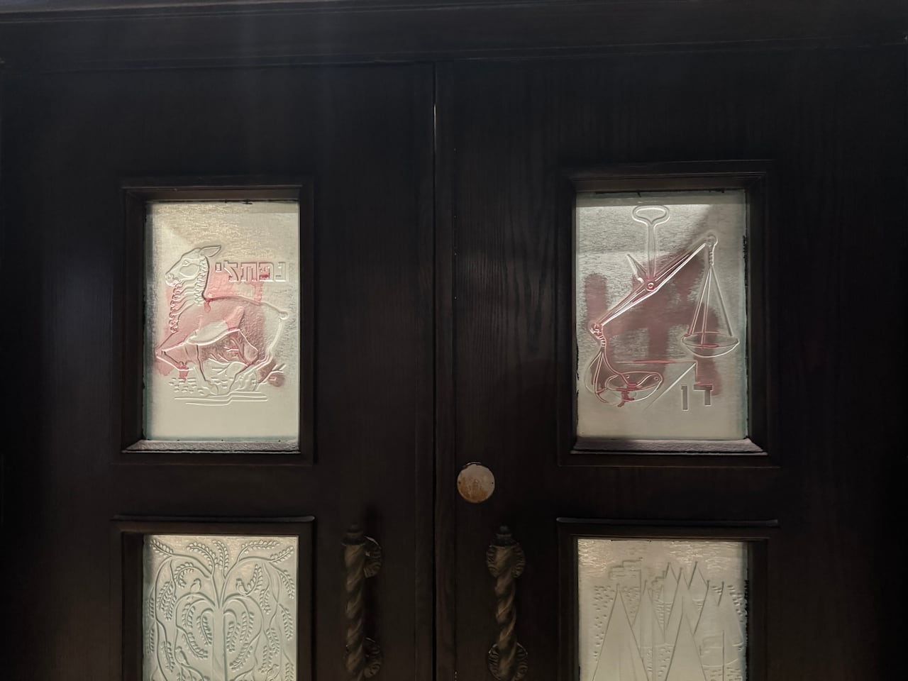 Red swastikas are painted in the windows of a door. 
