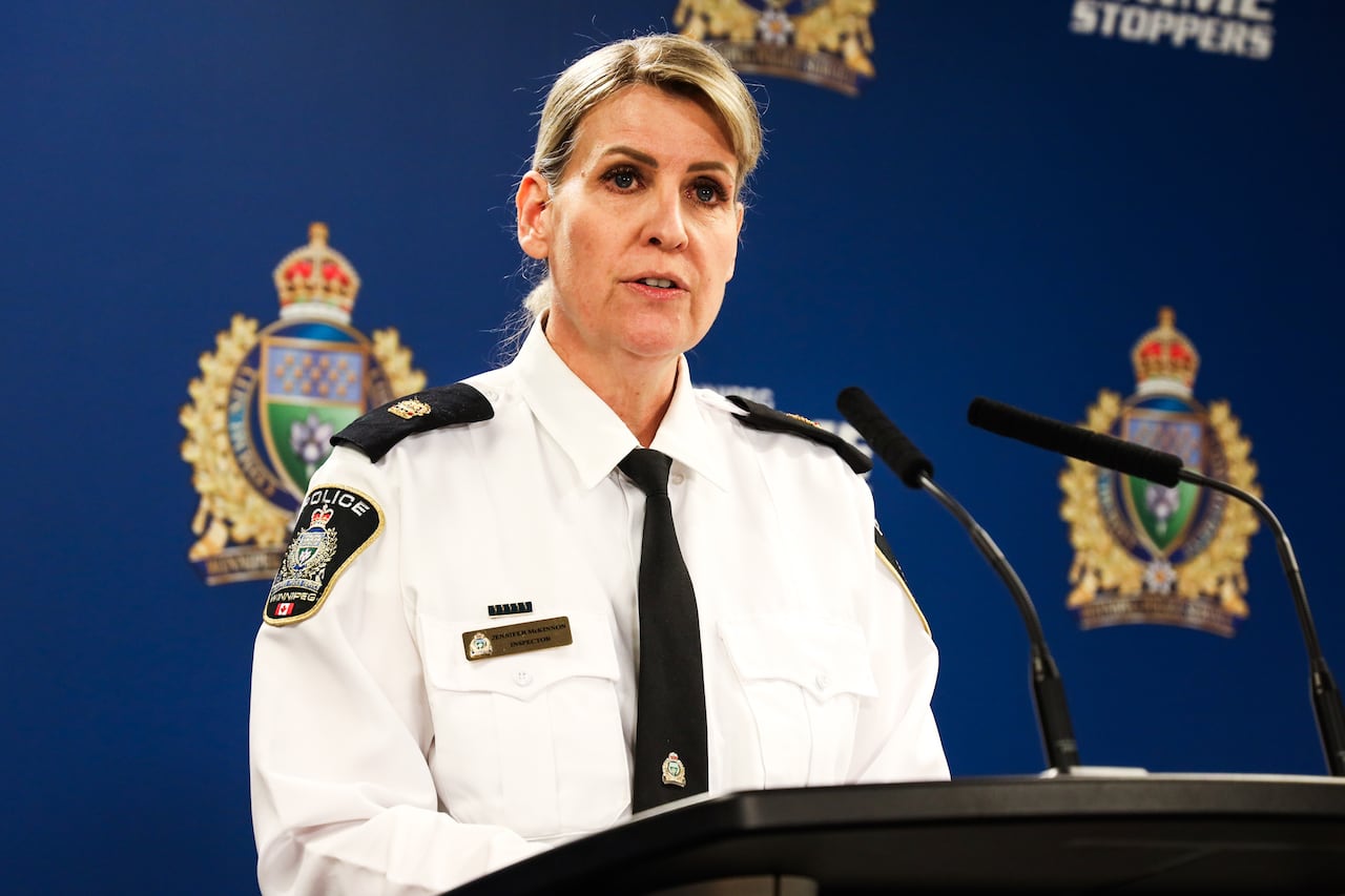 A police inspector speaks into a microphone at a lectern.