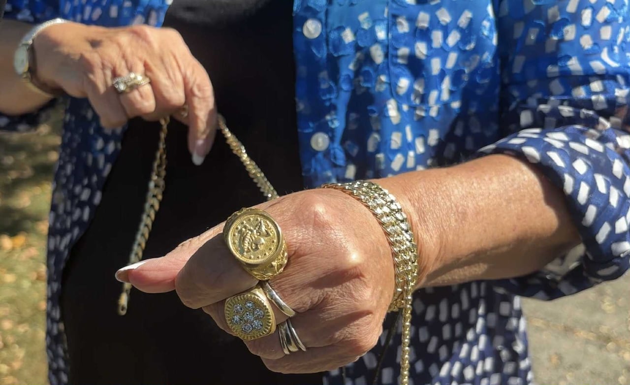 A woman wraps gold chains around her wrist
