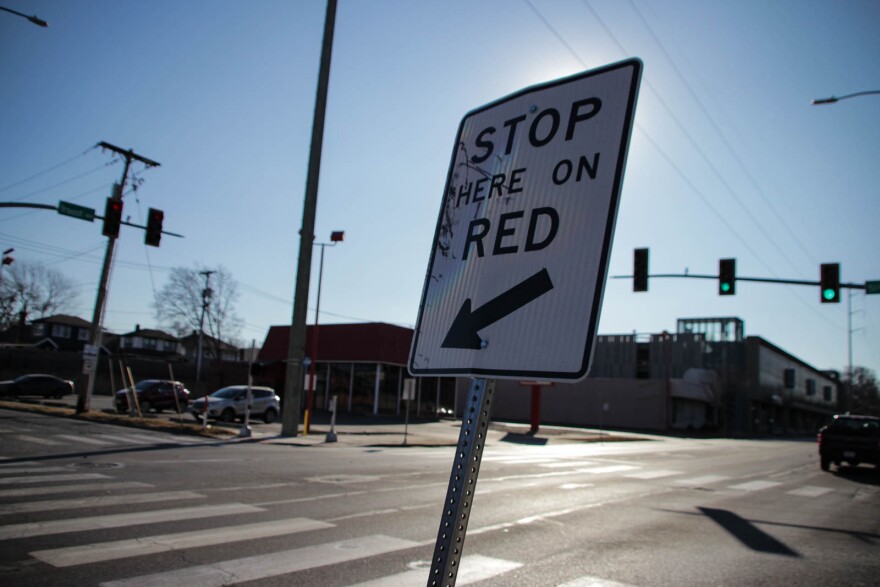A sign that says stop here on red sits on the sit of a street.