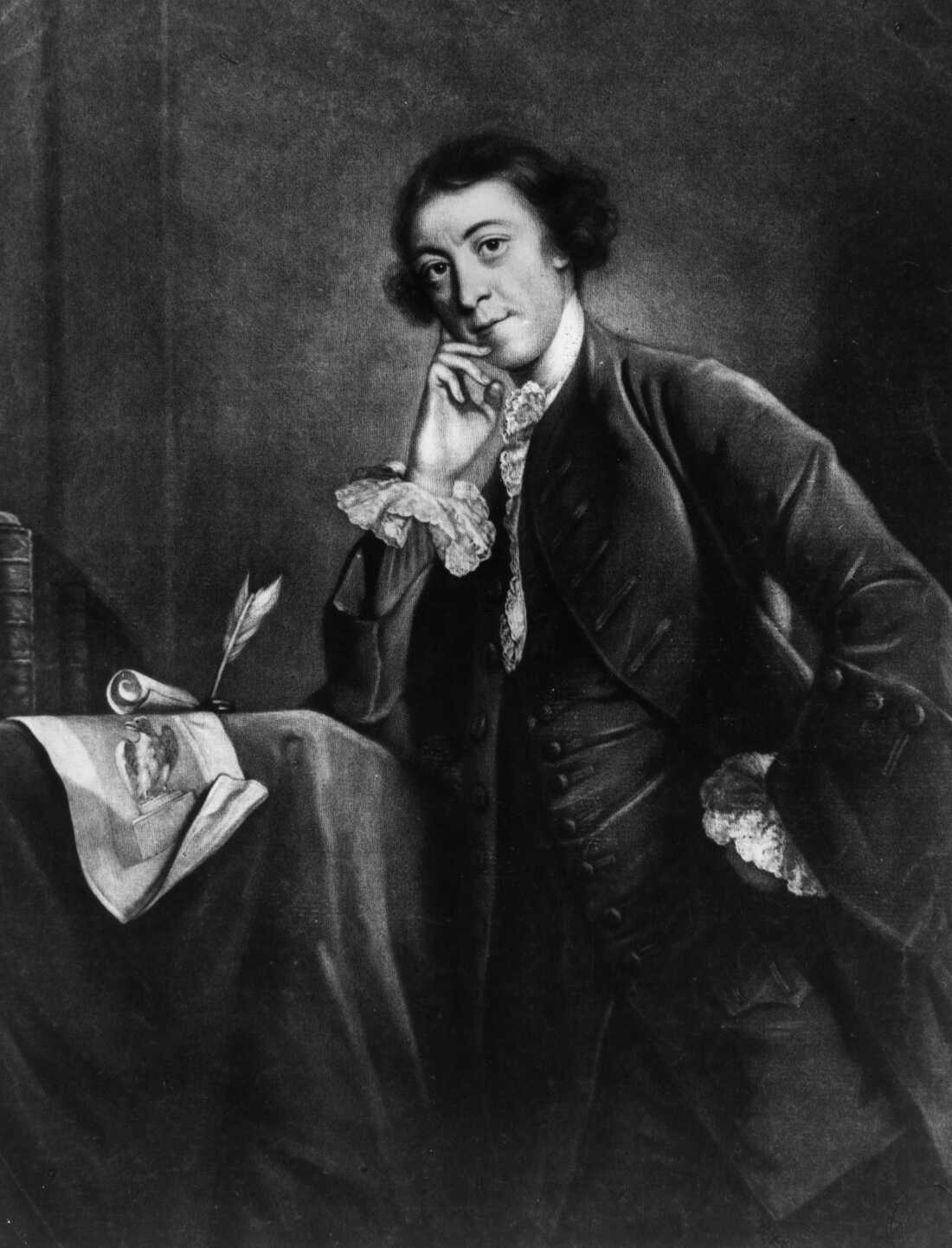 This black-and-white photo of a painting shows English politician and author Horace Walpole wearing 18th-century clothing and resting one elbow on a table. His other hand is in a waist-level pocket. A quill and scroll rest on the table.