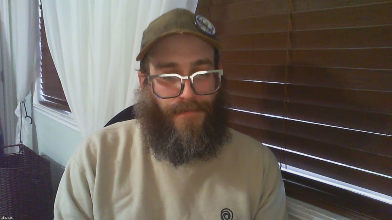 A bearded man with glasses looks dejected as he speaks to the camera. 