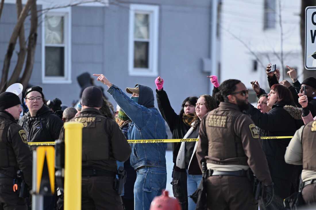 People protest as law enforcement officers attend to the scene of the shooting involving federal law enforcement agents on Wednesday in Minneapolis.