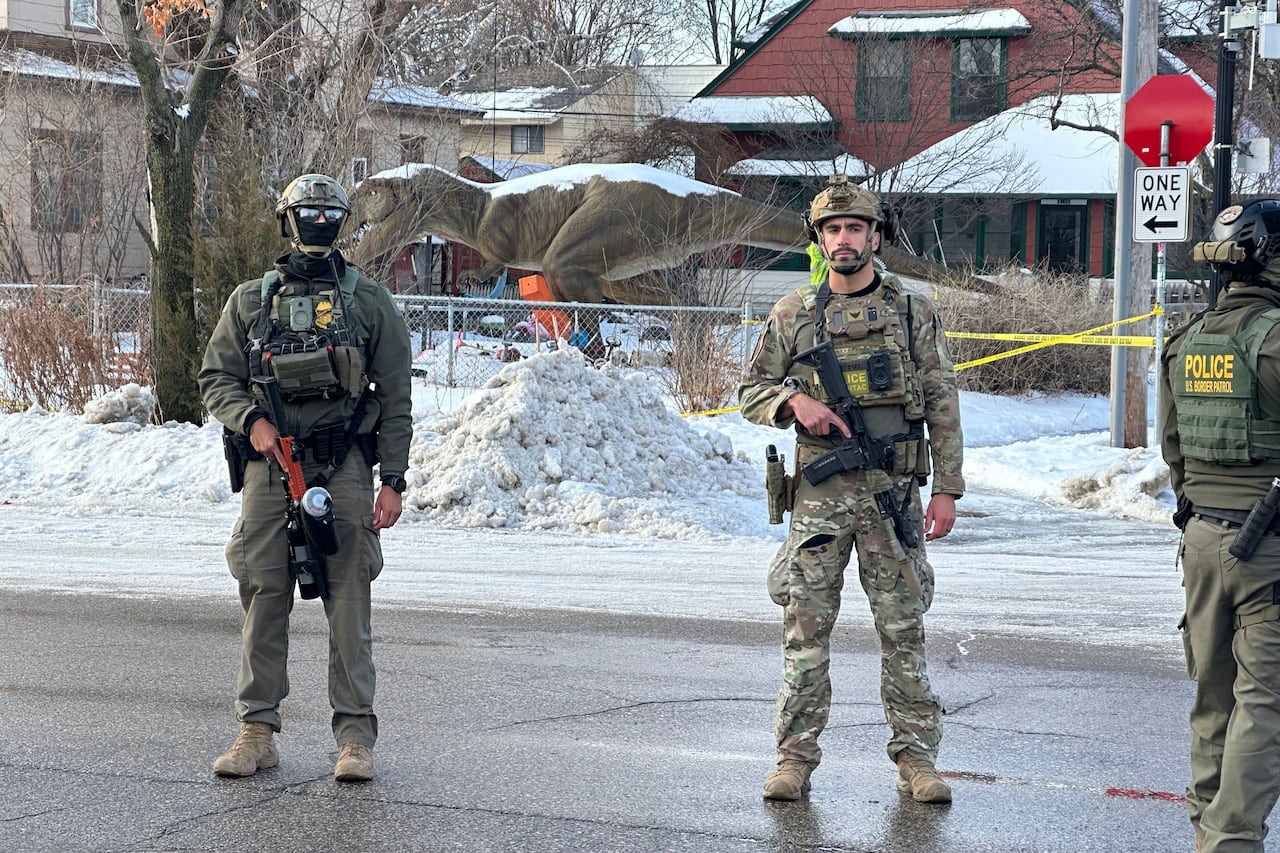 Heavily armed men in camo stand on street