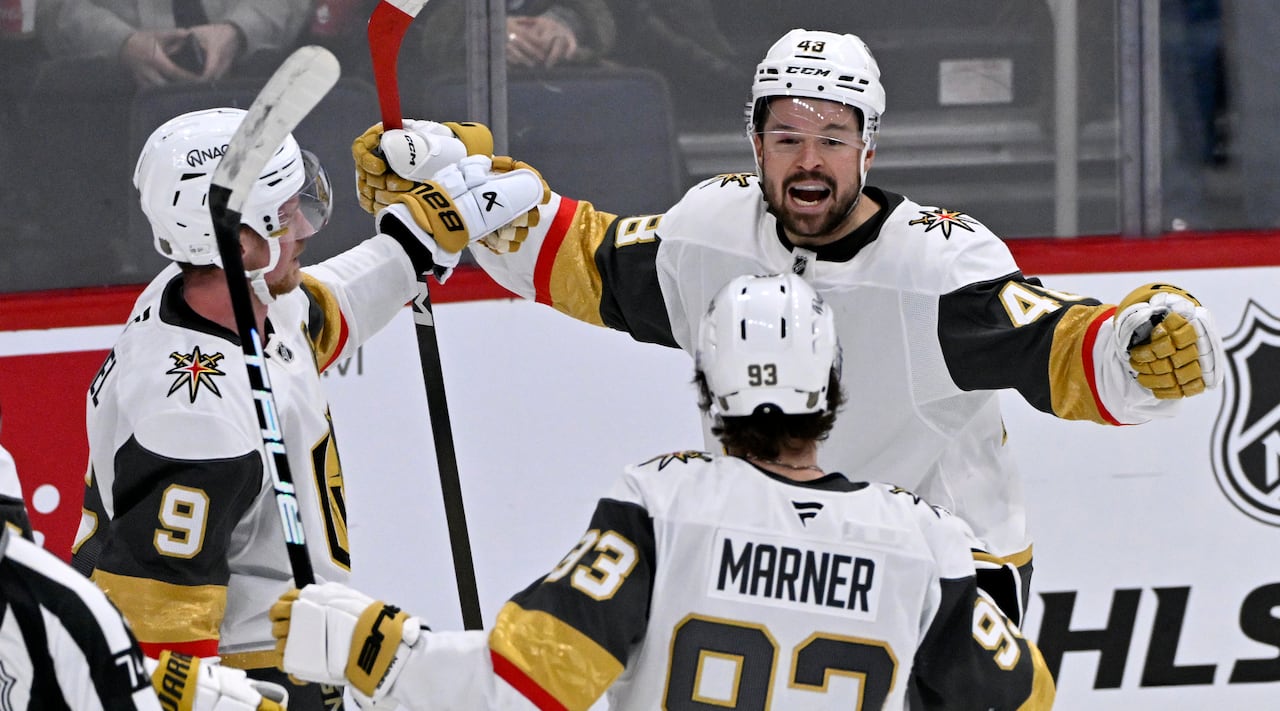 Three hockey players celebrate a goal.