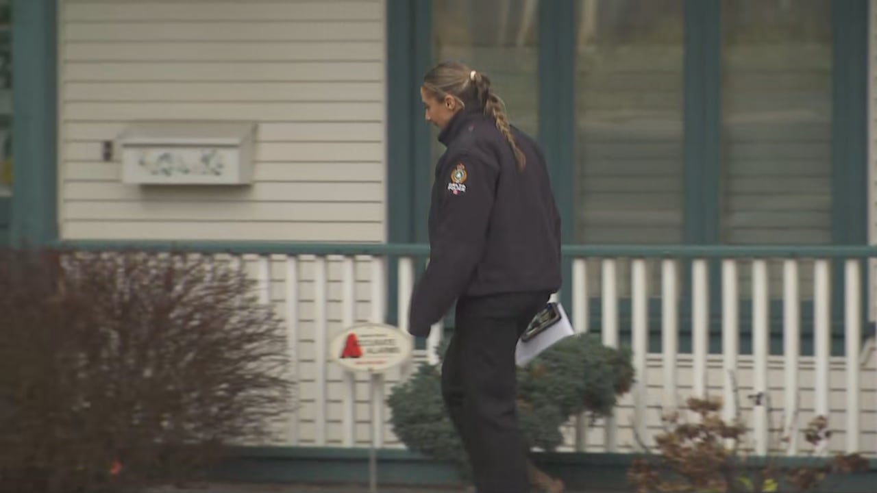 A police officer walks past a single-family home.