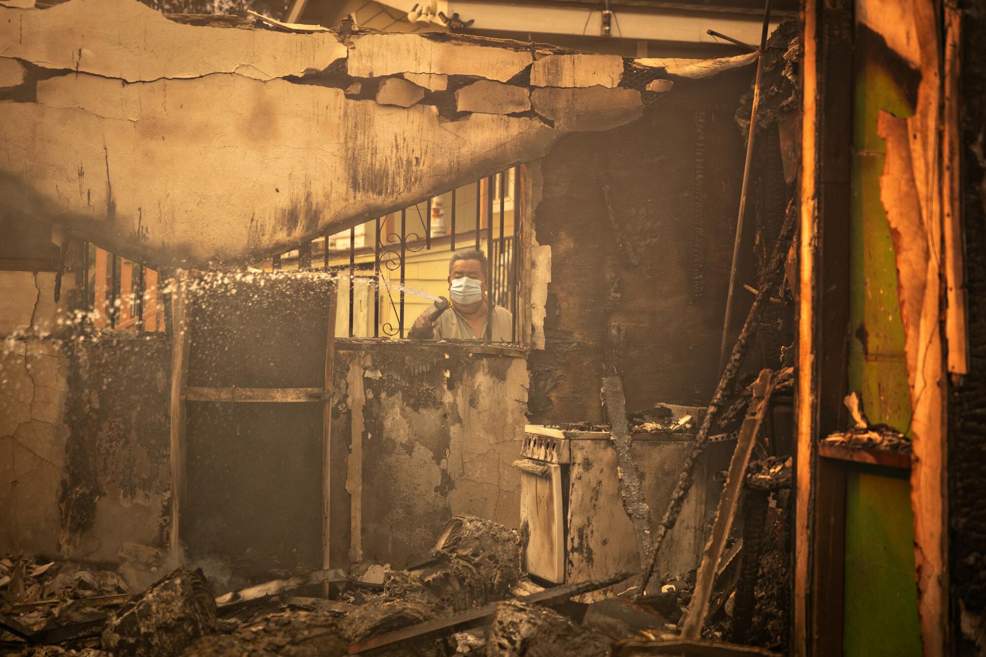 A man sprays water on a burning home