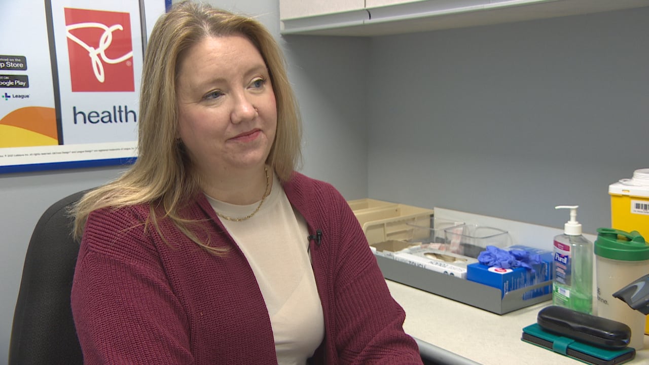 A woman sits in an office with medical supplies on a counter beside her.