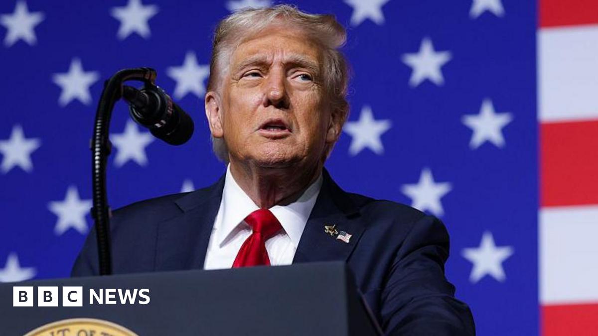 President Donald Trump speaks to an audience while standing in front of a brightly lit background with the American flag