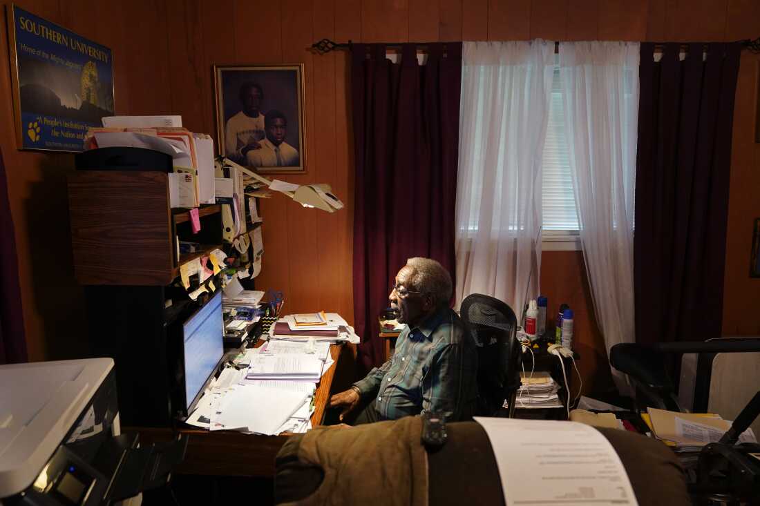 Press Robinson, a civil rights activist, sits at his desk in his home in Baton Rouge, Louisiana, on August 24, 2022. The desk has a computer monitor on it, as well as stacks of papers.