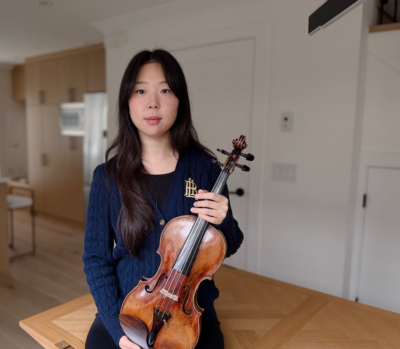 An East Asian woman holds a violin.