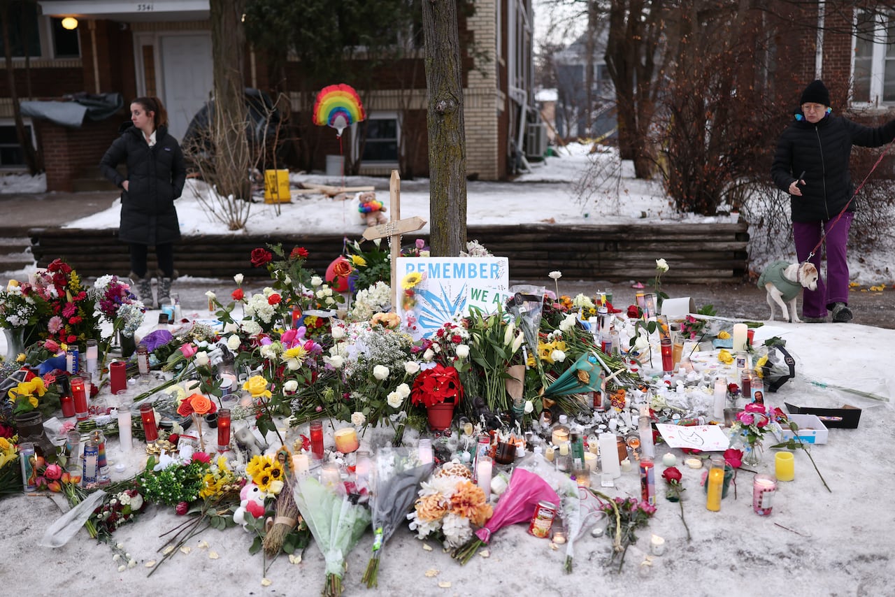 A memorial of candles, flowers and signs in the snow