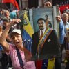 A woman standing among a crowd of people holds up a portrait of ousted Venezuelan President Nicolás Maduro in Caracas, Venezuela, on Saturday after he was captured by U.S. forces.