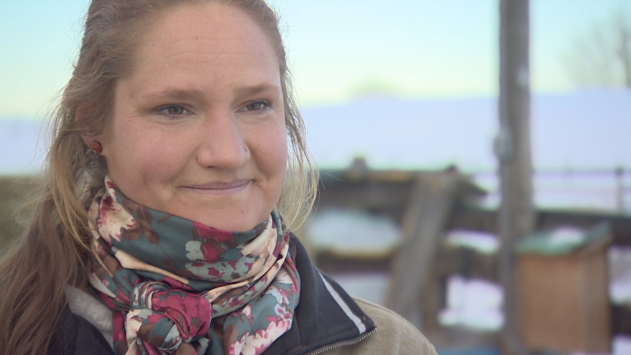 A woman with long brown hair and a scraft smiles.