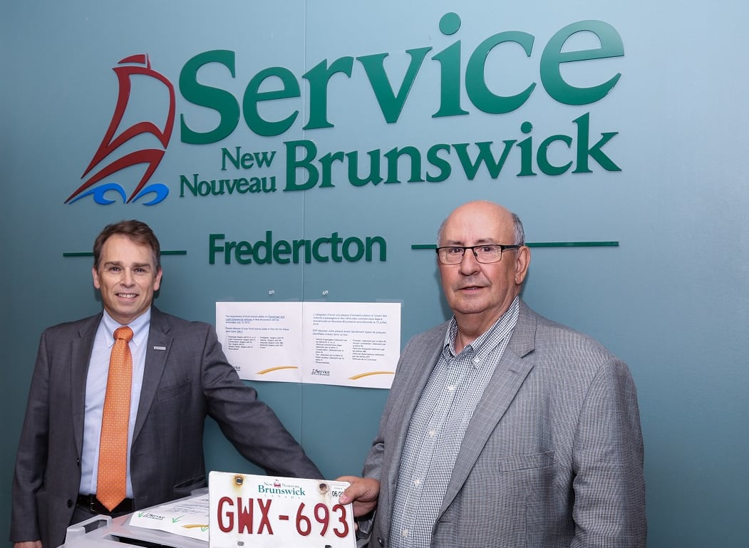 Two men holding a licence plate