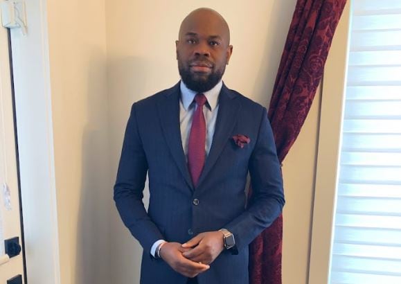 A man in a suit poses for a photo