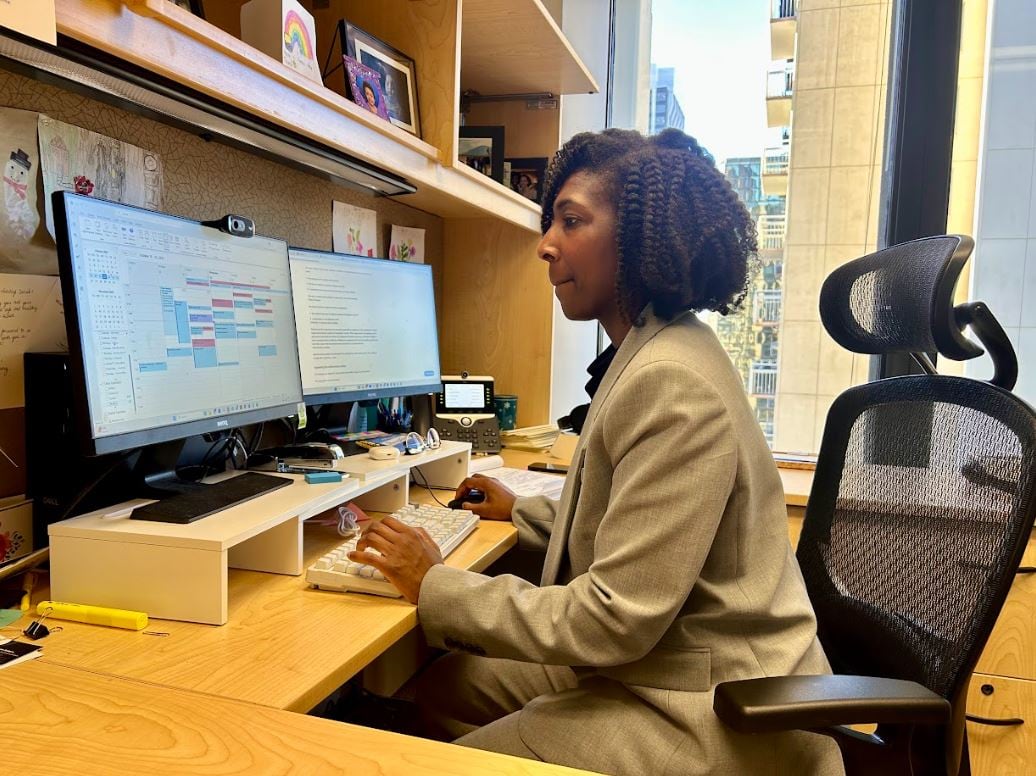 A woman sitting at a desk works at a computer