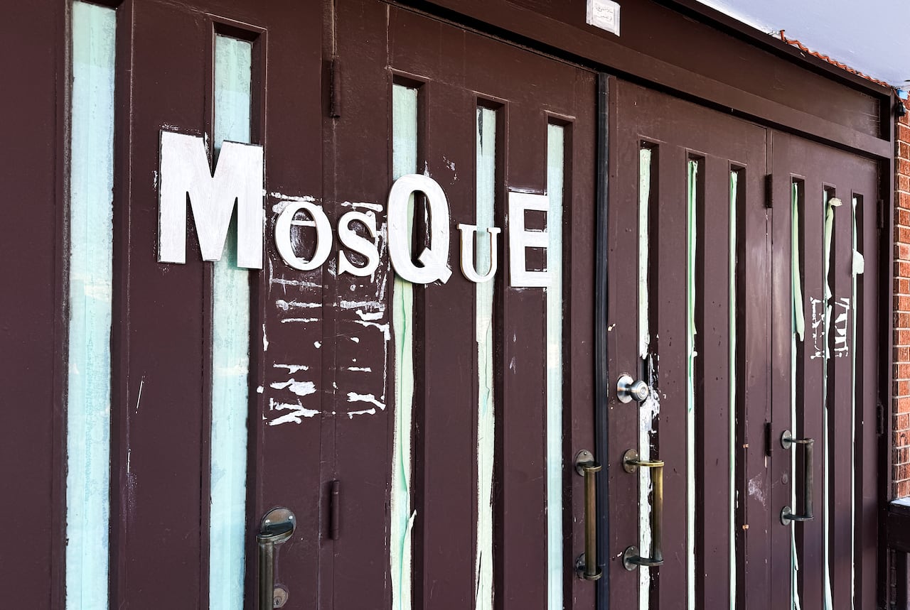 A closeup of brown doors on a building with the word "mosque" in white lettering.