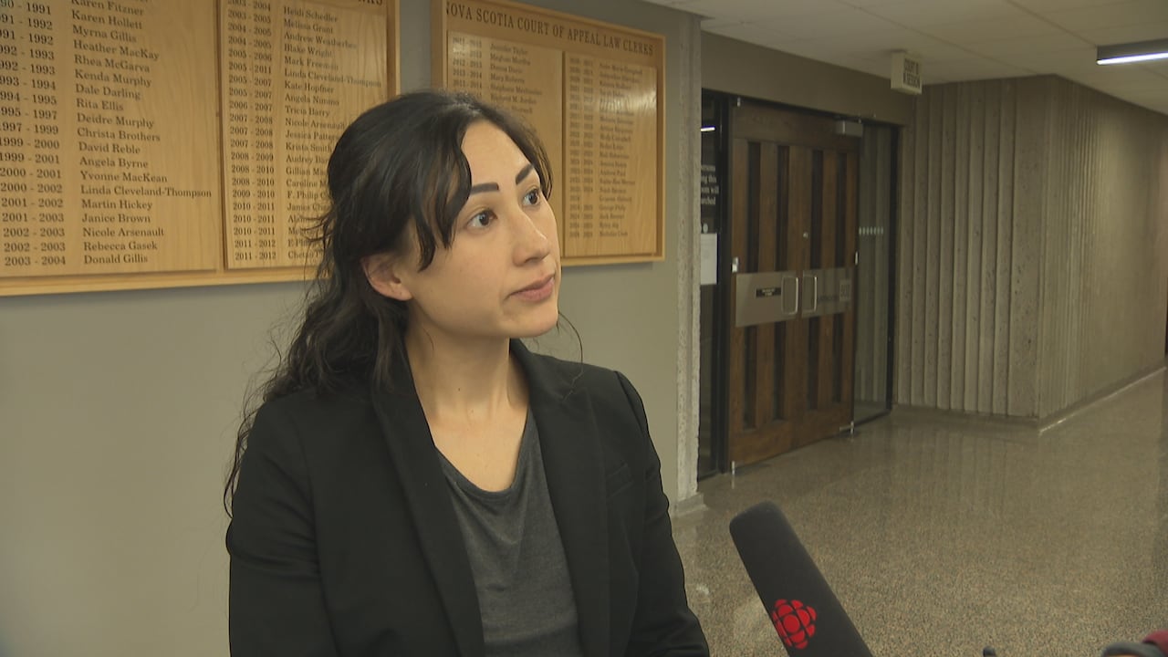 A woman stands outside a court room.