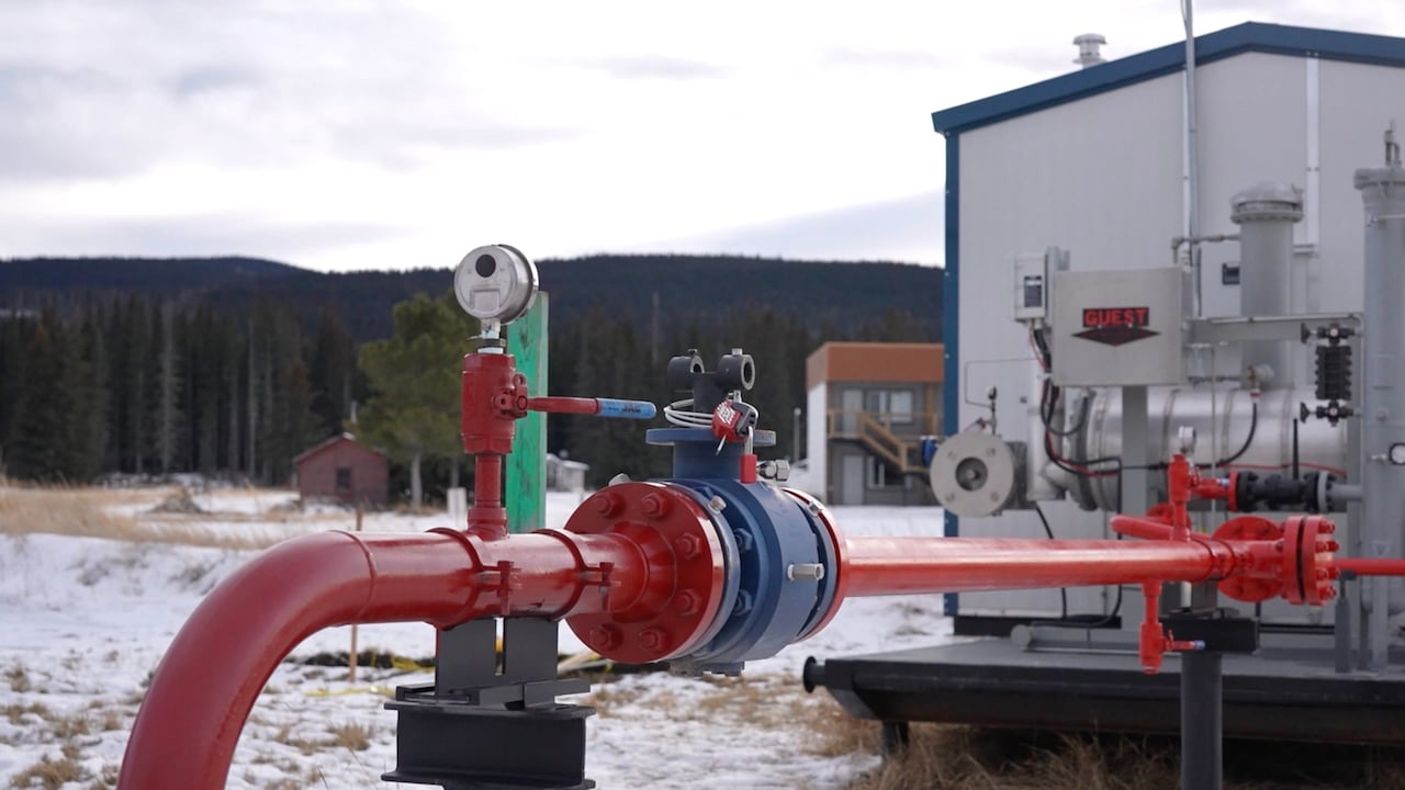 A pipeline station in an open ground with snow, mountains in the background