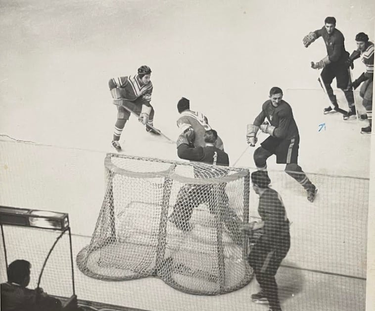Black and white photo of ice hockey players competing. 