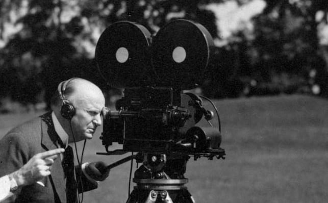 A black and white photo of a man with a film camera