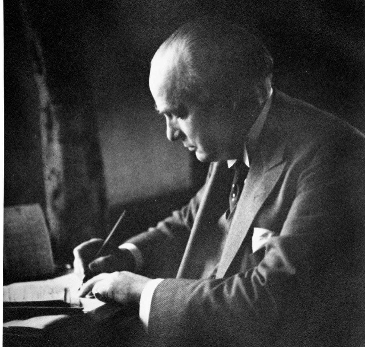 A black and white photo of a man writing.