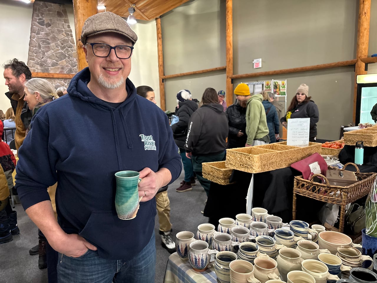 A man in a blue hoodie, holding a mug.