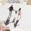 A blurry photograph of a family walking and holding hands, as seen from a high angle. Two parents walk, holding the hands of their child who walks between them. The photo has a dreamy quality. 