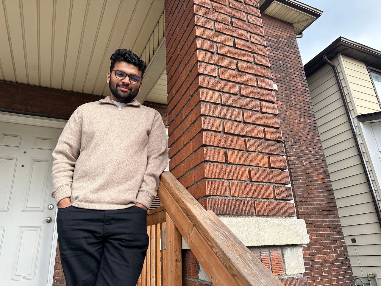 A man standing against a brick wall.