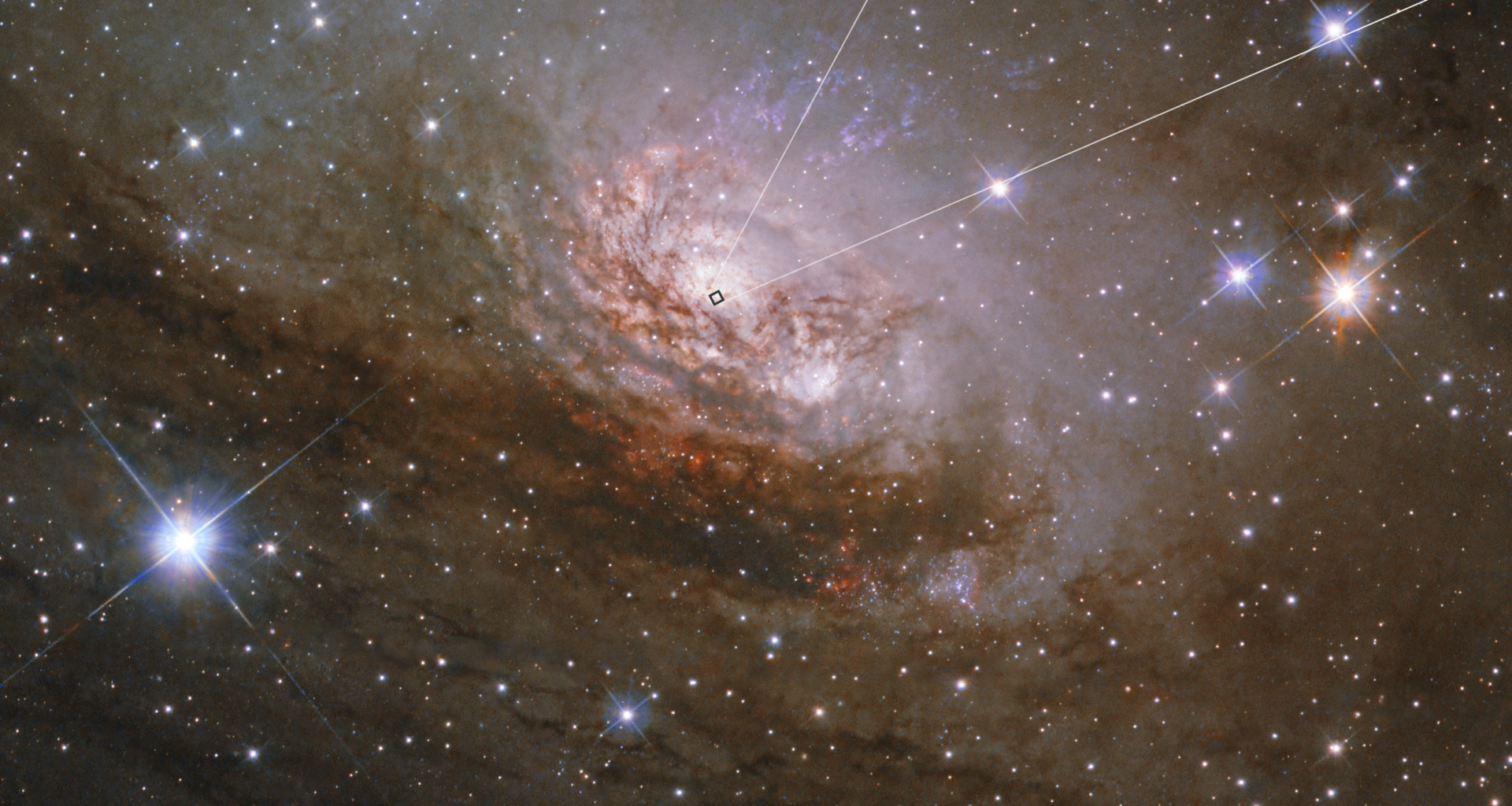 Image shows a large spiral galaxy that that has a bright white center, with several lanes of reddish-brown dust and gas in between faint white arms. The galaxy takes up the center third of the frame. There are several thousand stars, some with diffraction spikes, scattered around the image. This image is labeled Hubble. A small box outlining an area at the center of the galaxy leads a pullout square at the top right. The image, labeled Webb, is dark with a white glowing oval at the center.