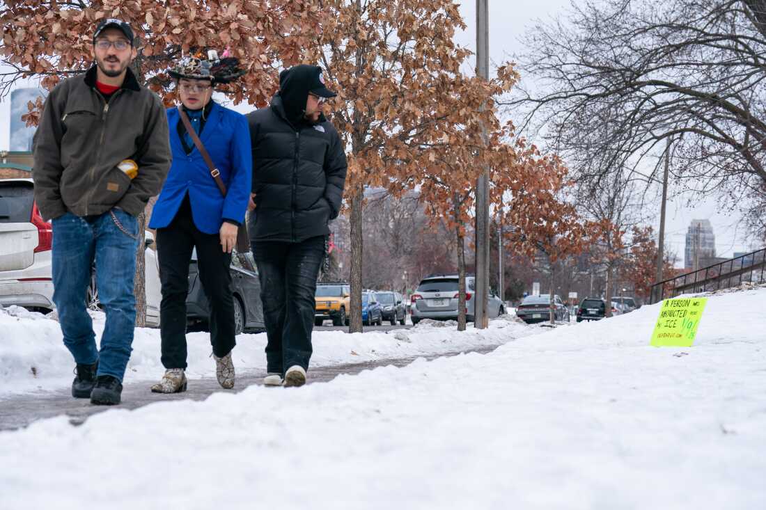 Three men observe a sign marking the site of an ICE abduction outside of Our Saviour's Lutheran Church in Minneapolis on Sunday.