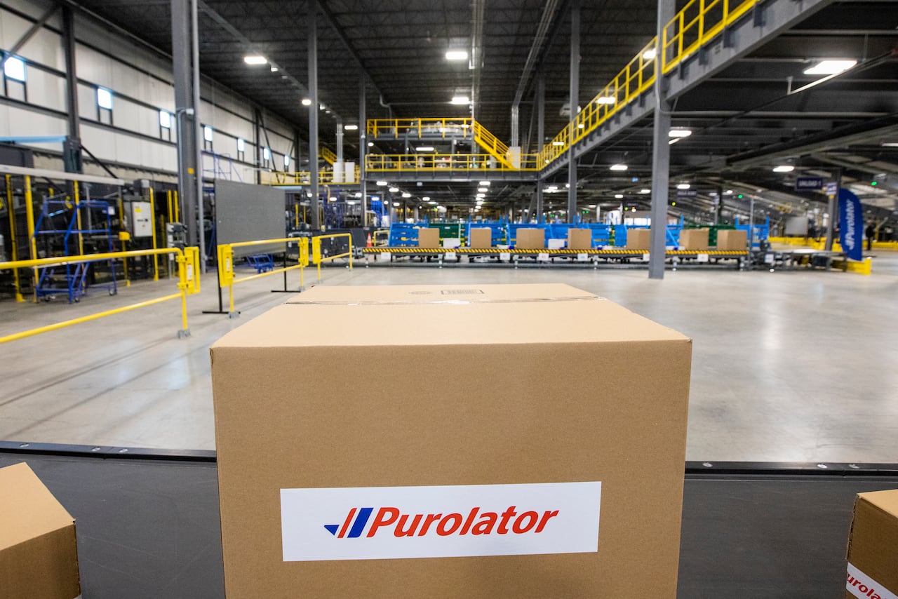 A box with a 'Purolator' logo on it sits in the foreground, as a large shipping facility is pictured behind it.