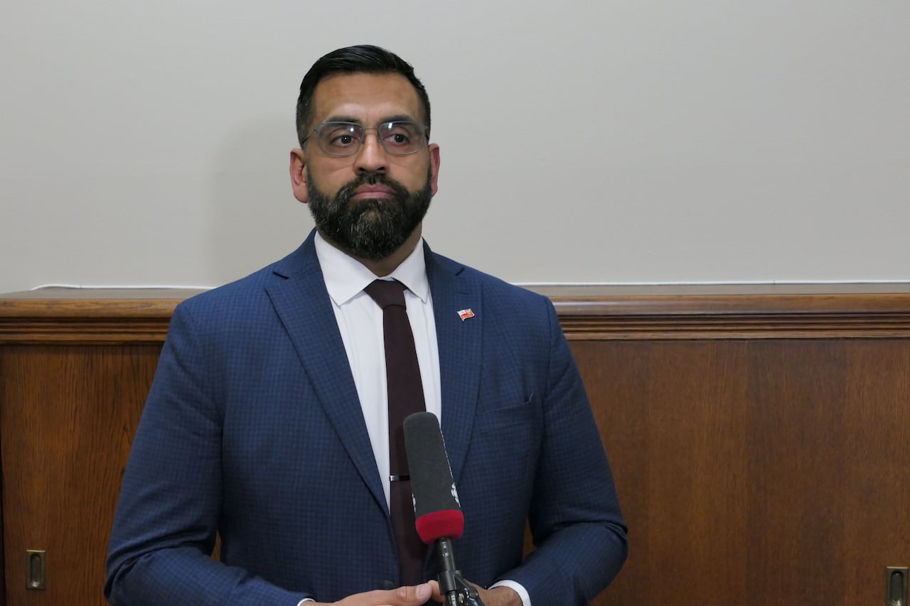 A man in a blue suit speaks into a microphone.