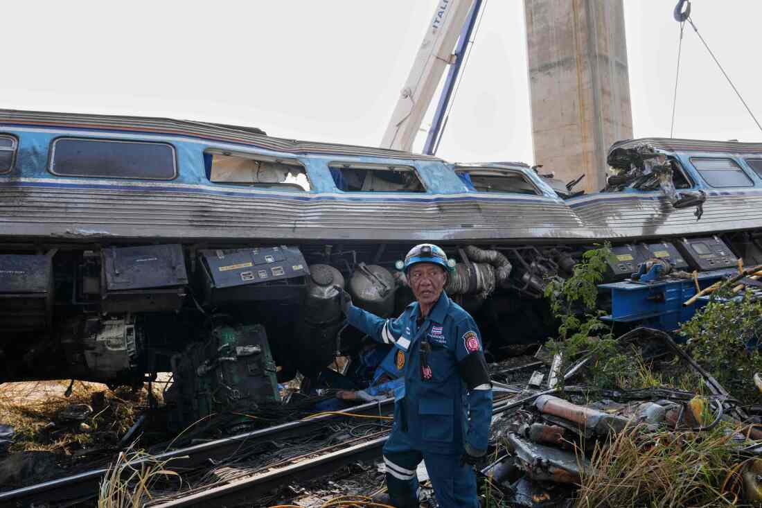 A rescuer stands near the wreckage after a construction crane fell into a passenger train in Nakhon Ratchasima province, Thailand, Wednesday, Jan.14, 2026.