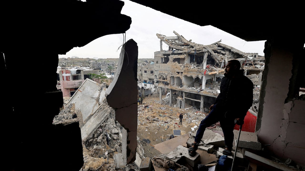 A man stands at the edge of a destroyed building.
