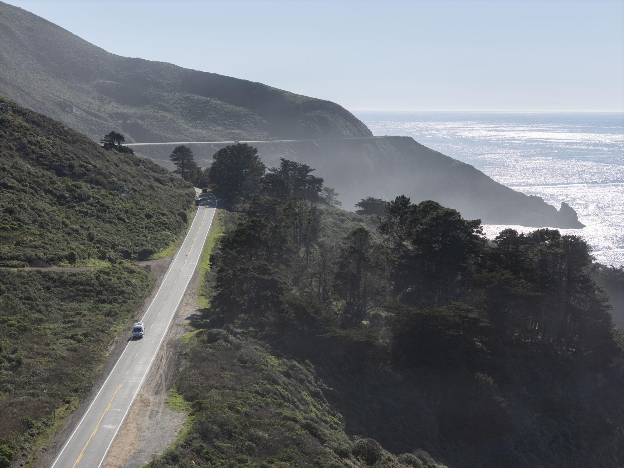 aerial view of a lone car drives on a coastal highway