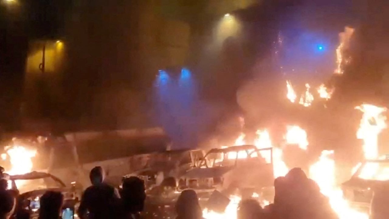 In this screen grab obtained from a social media video released on January 9, 2026, protesters gather as vehicles burn, amid evolving anti-government unrest, in Tehran, Iran.