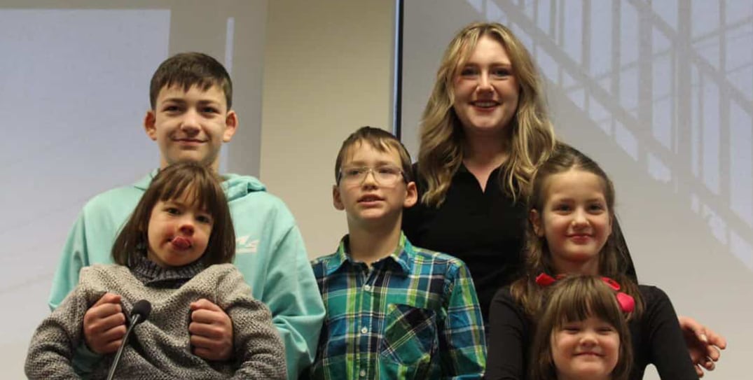 A family of five siblings smiling. 