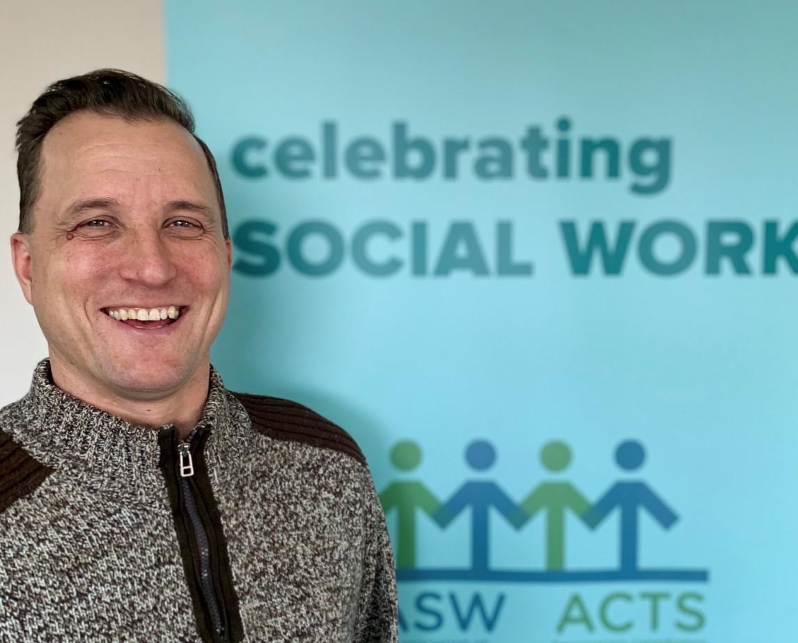 A man standing in front of a blue banner