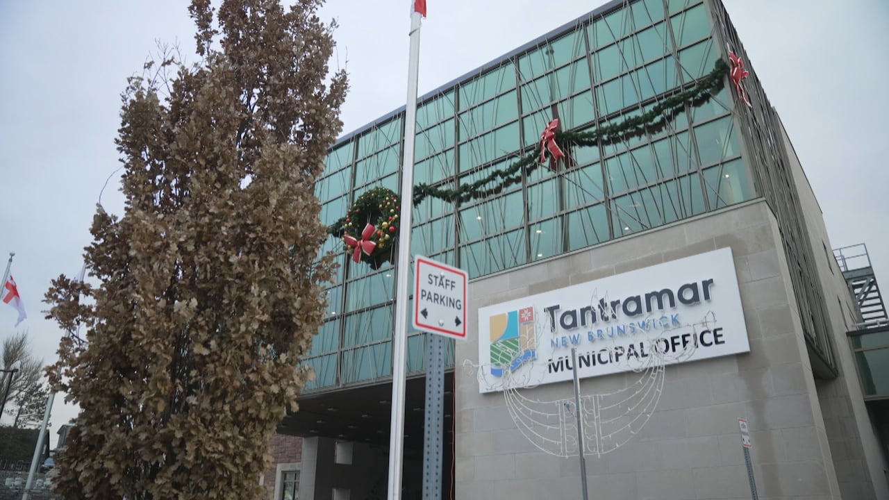 The exterior of a building with a sign on the front that says "Tantramar Municipal Office." The building is grey and has many windows, as well as Christmas decoations.