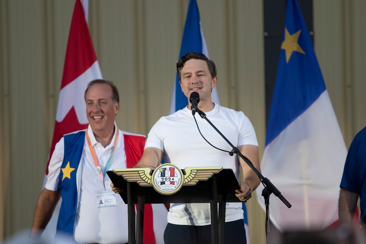 Conservative Party Leader Pierre Poilievre, flanked by former Conservative MP Chris d'Entremont, speaks to the crowd prior to the National Acadian Day concert at the airport in Yarmouth, N.S., on Thursday, August 15, 2024. 