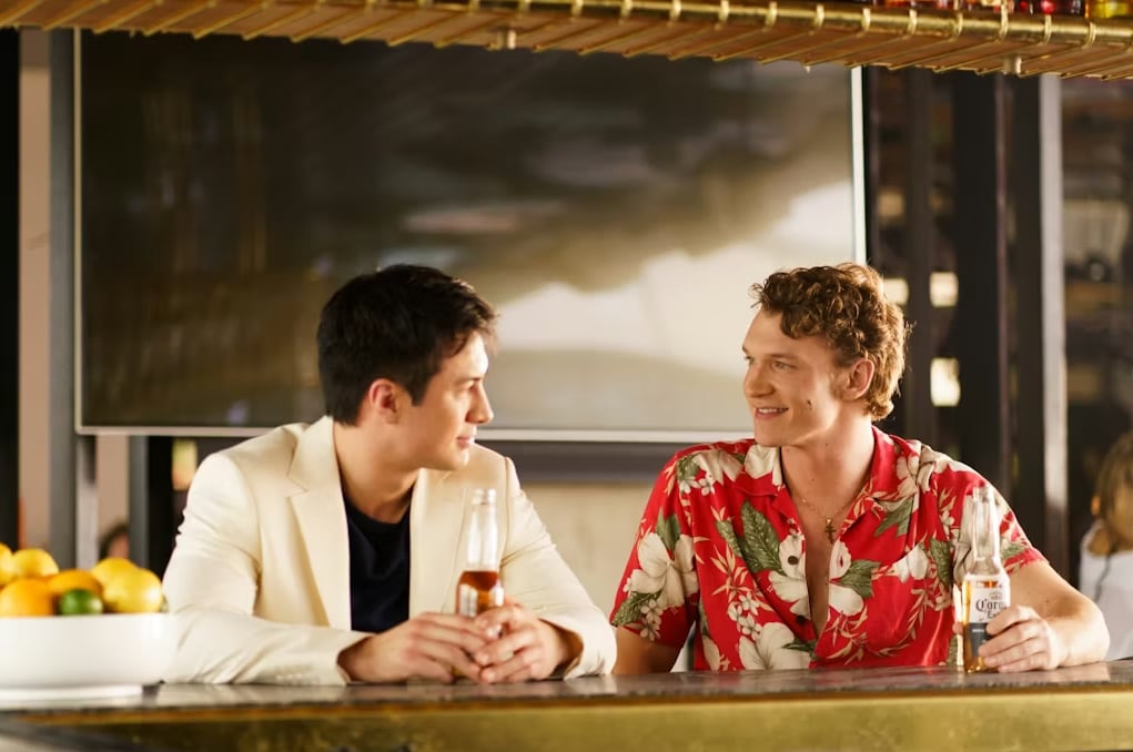 Two men sit at a bar with drinks
