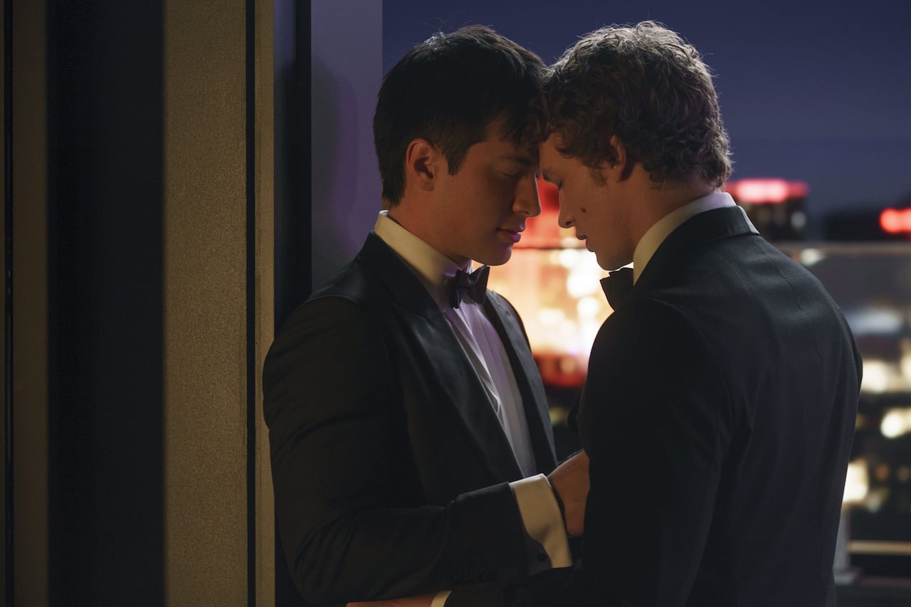 two men in tuxedos hold their heads together in a gentle embrace