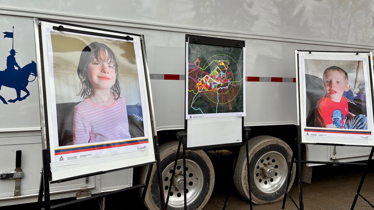 Three posters on stands, one of a little girl, one of a map with colourful lines and another of a little boy.