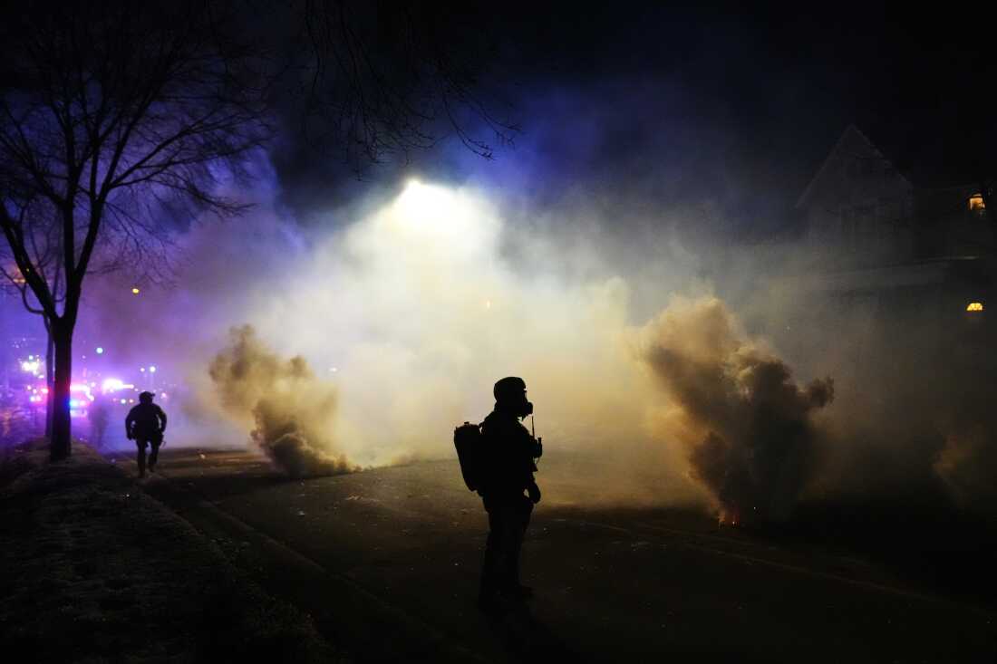 Law enforcement officers stand amid tear gas at the scene of a shooting Wednesday in Minneapolis.