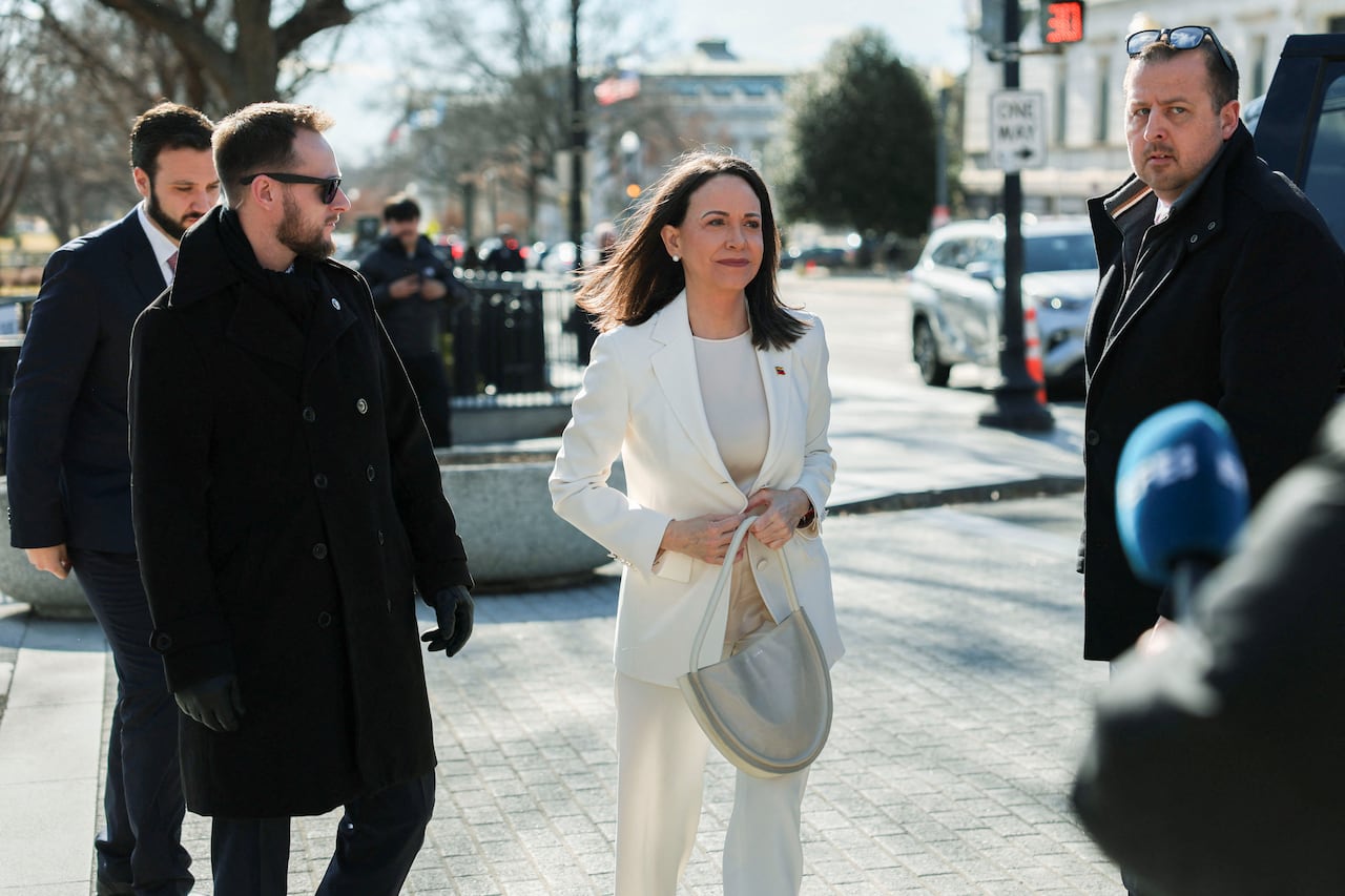 A woman wearing a white suit stands next to several men.
